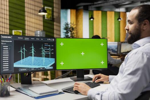 Green tech company technician adjusting windmill farm layouts using isolated screen PC. Engineer using chroma key computer to calibrate wind turbines power plant for higher efficiency photo