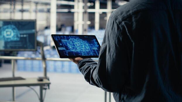 Data center system administrator monitors deep learning processes, reviewing operational metrics. Server room IT professional wears audio headset, reviews neural networks reports, camera B photo