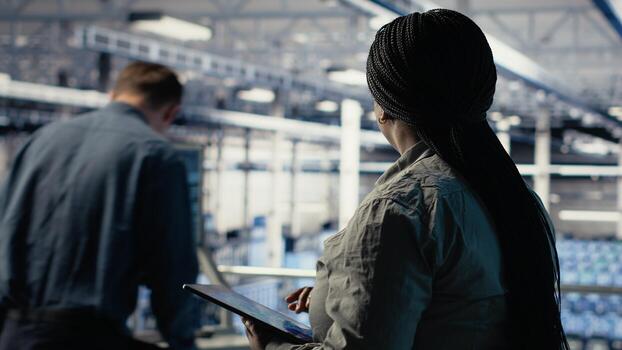 Data center employee monitoring infrastructure processes, reviewing operational metrics. Server room IT worker reviews high tech infrastructure equipment rigs reports during inspection, camera B photo