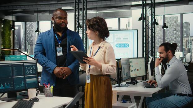 Diverse workers team use digital tools and analytics to improve growth strategy, reviewing financial insights on tablet to foster innovation and development in a modern office environment. photo