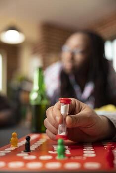 Close up on hand of caucasian man placing hourglass on board, ready to play. The image conveys relaxed, fun atmosphere, highlighting use of timer in playful context of friendly game. photo