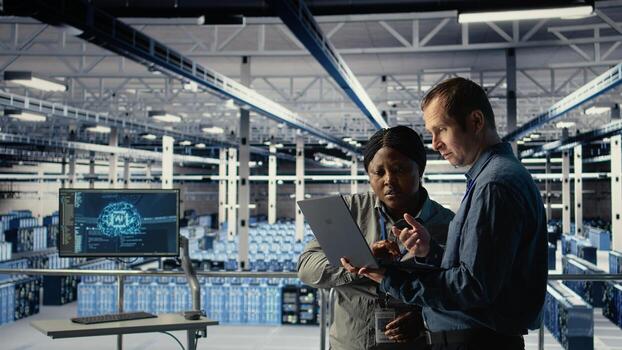 Team of engineers in server hub optimizing deep learning AI systems handling tasks. Teamworking data center colleagues adjust artificial intelligence model parameters using device, camera A photo