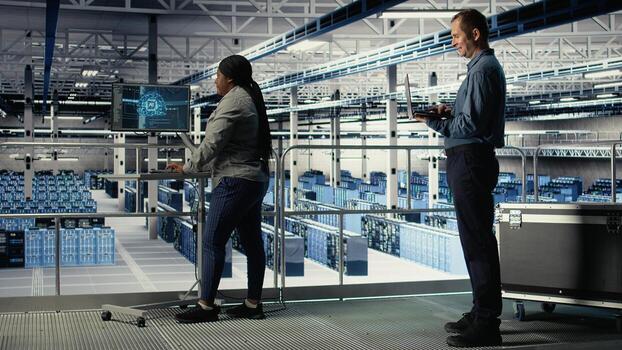 Data center software developers monitor deep learning processes, reviewing operational metrics. Server farm IT specialists work together to review neural networks reports during inspection, camera A photo