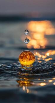 A drop of water falling from a golden object into the ocean photo