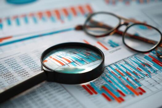 Magnifying glass and eyeglasses on financial documents photo