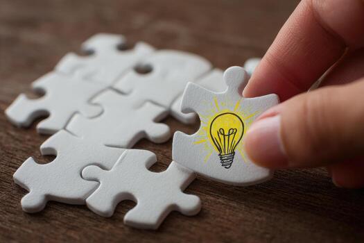 A person is placing a puzzle piece with a light bulb on it photo