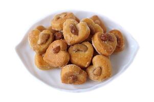 delicioso anacardo nuez galletas, además conocido como Singapur galletas, arreglado en un blanco lámina. en forma de corazón, dorado marrón, y rociado con azúcar, Perfecto para aperitivos, postres, o panadería promoción. foto