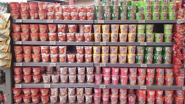 Various kinds of local brand instant noodles cup display on shelf at Happy Harvest Supermarket Summarecon Mall. Bekasi, West Java, Indonesia - August 7 2025 photo