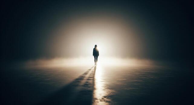 Lone figure walks towards bright light in dark environment. photo