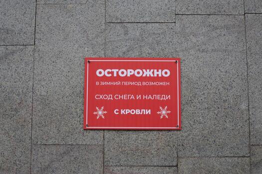 Taking care of citizens with warning sign. Sign in Russian stating possible danger of snow and ice falling from roof in public place. Do not go near building in winter to avoid snow falling from roof photo