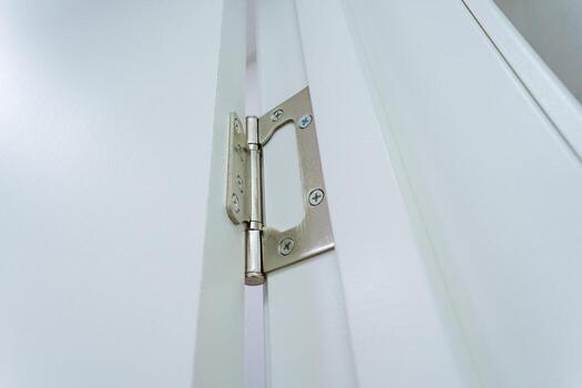 A detailed closeup of a door hinge attached to a pristine white frame truly showcases the intricate mechanism, highlighting the importance of architecture and hardware in the renovation process photo