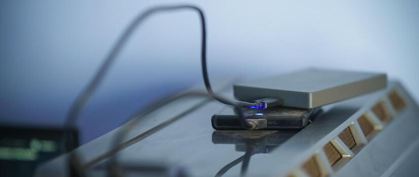 HARDDISK, HARDDRIVE Close-up view of electronics and cable connection setup, showcasing technology equipment and USB wire in a studio or home workspace environment photo