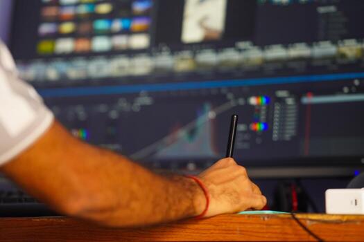 A person editing a using a stylus and tablet in front of computer screen, representing modern production and digital creative work photo