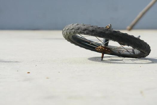 Black cycle tire spinning on cemented ground, frozen in motion, showing movement and balance with minimal background photo