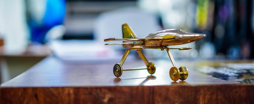 Golden Airplane Model Placed on Wooden Surface with Blurred Background selective focus image photo