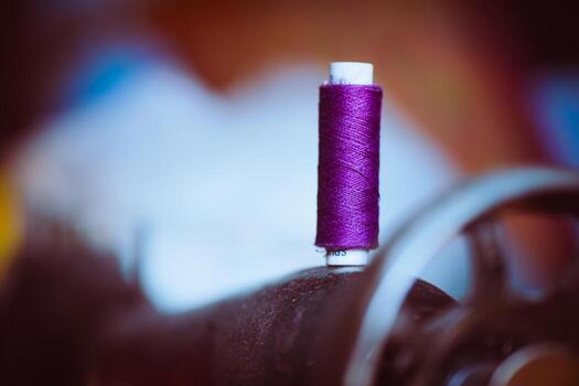 Vibrant purple thread spool on antique sewing machine, macro photography showing the intricate thread texture and garment tool aesthetics photo