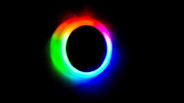 Circular neon light effect featuring a vibrant multicolor gradient emitting from a dark center. Perfect for themes of energy, technology, and modern design. photo