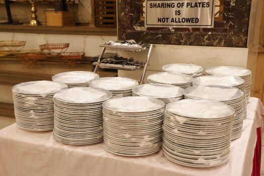 Stacked Plates on Buffet Table with Hygiene Guidelines Displayed photo