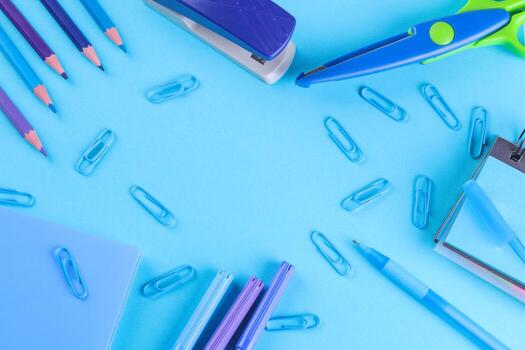 Various stationery in one color scheme on a bright paper blue background. Top view photo