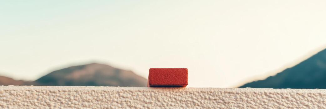 Red block placed on a white ledge with mountains in the background at sunset photo
