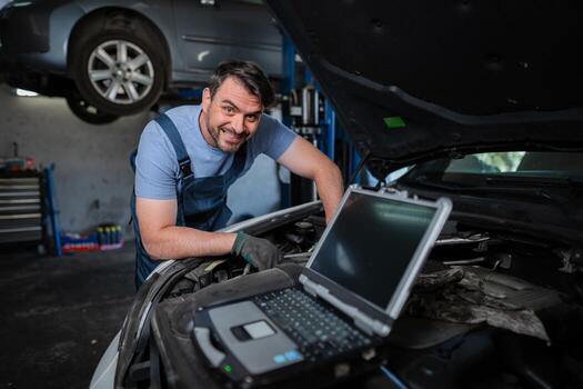 Car mechanic using a computer to diagnose a car engine problem photo
