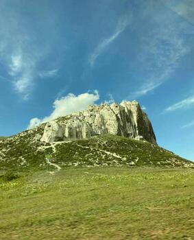 Landscape with a large waste heap on the horizon. Green trees are visible in the foreground, and fields stretch beyond them. photo