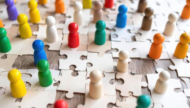 Colorful wooden figures stand on jigsaw puzzle, symbolizing unity and diversity. This vibrant scene captures essence of collaboration and connection among individuals photo