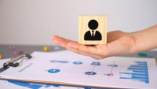 Wooden block with business person icon on hand over clipboard with business chart and graph, concept of human resource management and business strategy planning with soft light photo