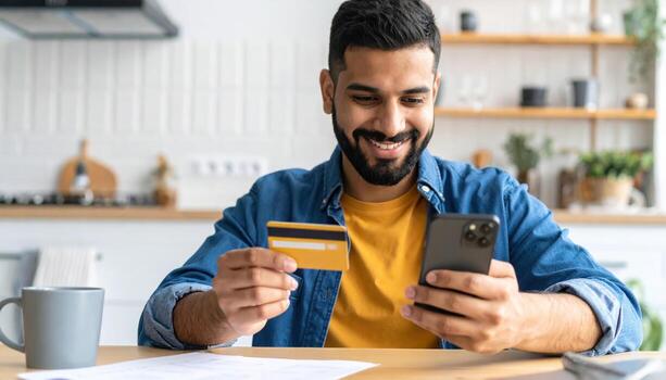 Man using credit card and smartphone at home photo