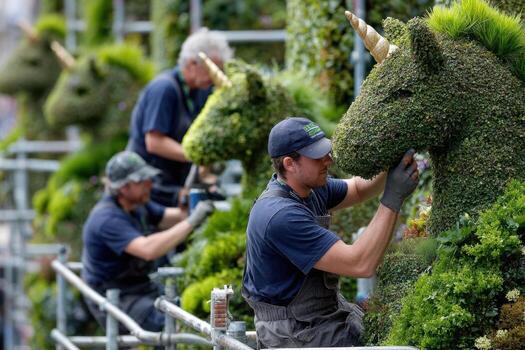 Workers creating living unicorn sculptures at a floral event in a garden setting photo