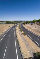Scenic highway view with clear blue sky and vehicles traveling in distant landscape during midday photo