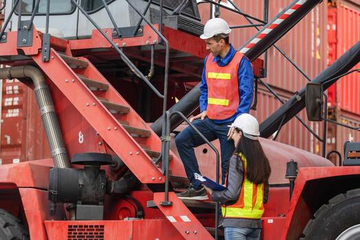Port workers conducting a safety inspection on a reach stacker at a commercial dock, Female manager discusses shipping logistics with a male crane operator at a busy container terminal photo
