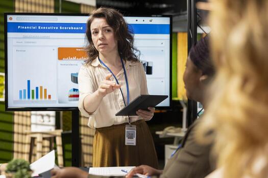Diverse businesswomen working side by side to review data on TV monitor in the boardroom, collaborating on a strategic presentation that could feature projected reports or success metrics. photo