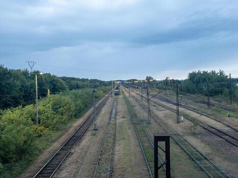 ferrocarril unión y traspuesta yarda con múltiple pistas, gastos generales de cadena y señales en verde paisaje debajo nublado cielo. foto