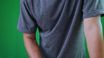 en man visas till vara framställning till arbete, plockning något upp, i en grå t-shirt står i främre grön skärm, eller i de mitten av ett handling. för redigering och presentationer video