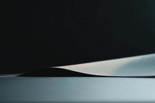 Curved black paper lying on a dark surface emphasizing texture and shape photo