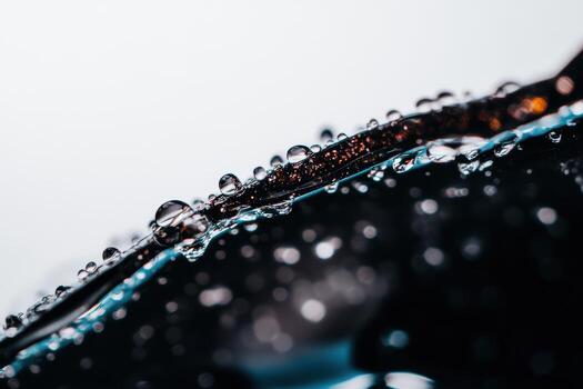 Close-up view of water droplets on a dark surface reflecting light photo