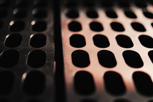 Close-up view of metallic surface with evenly spaced perforations in dim light photo