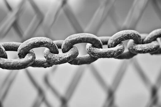 Close-up view of rusty chain links against a metal fence backdrop photo