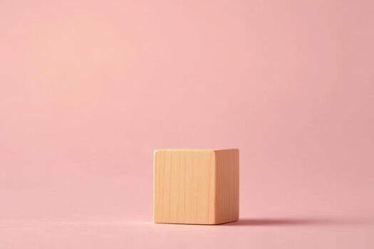 Simple wooden block placed on a soft pink surface with natural lighting photo