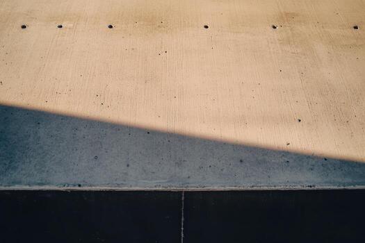 Concrete surface illuminated by sunlight casting a shadow in urban setting photo