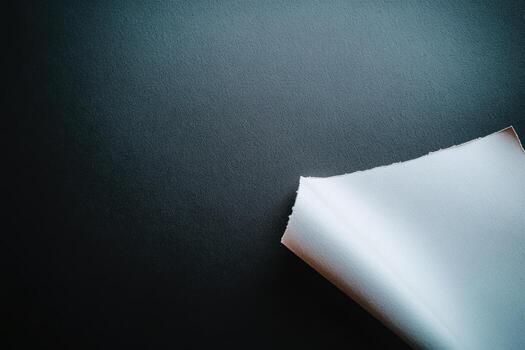 Textured surface with a white sheet partially folded in a dark setting photo