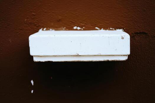 Simple white rectangular box mounted on a brown wall photo