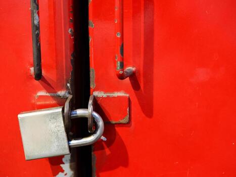 Silver Padlock on a Red Metal Door. concepts of security, protection, and privacy, and is ideal for conveying ideas related to safety, storage, and locked access. photo