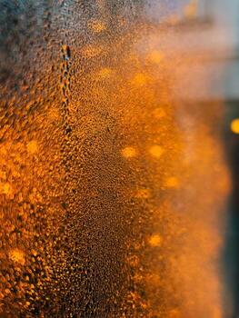 Water droplets clinging to surface reflect warm orange light, creating captivating abstract background with stunning gradient effect and intricate textures that evoke serene atmosphere. Texture shift photo