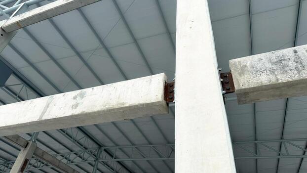 Wide view of concrete beam-to-column bolted connection with steel plate, showing structural engineering details and industrial building framework. photo
