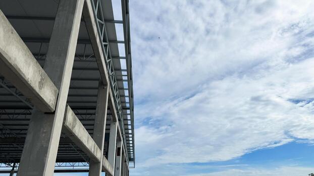 Concrete building column and steel frame structure under construction with wide blue sky and cloud background, architecture and engineering concept. photo