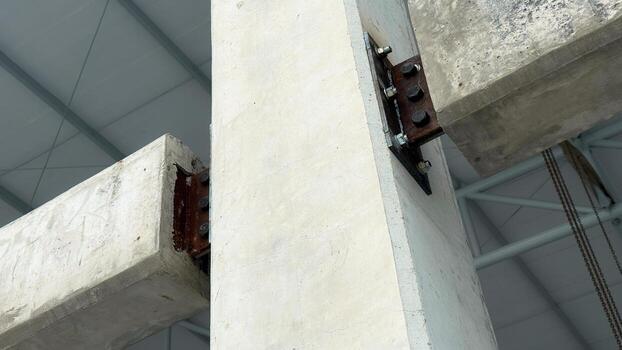 Structural connection of concrete beams to a column with steel plate and bolts, showing engineering details in construction framework. photo