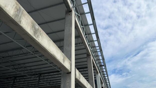 Concrete column and horizontal beam connection with steel roof structure, under construction building with modern engineering framework and sky background. photo