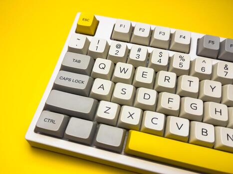 White mechanical keyboard with key on bright yellow background, minimalism, keyboard buttons. A keyboard with a yellow key on the bottom left photo